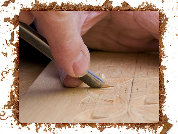 An image of a wood carver using a carving gouge for a project.